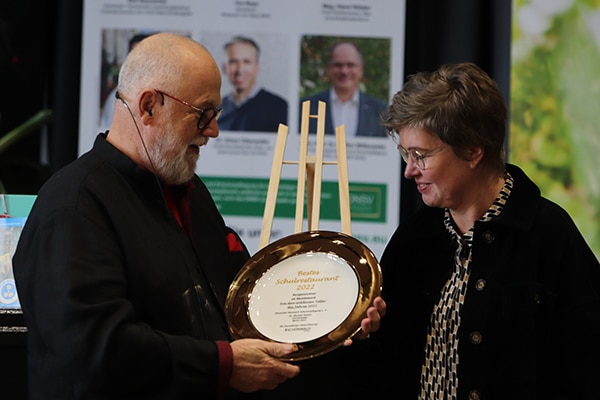 Der Vorsitzende des DNSV Dr. Michael Polster übergibt den „Goldenen Teller 2022“ an Doris Ostmann, Leiterin Mensateam OBS Emstek (Quelle: Friedrich Schmidt/Universität Vechta)